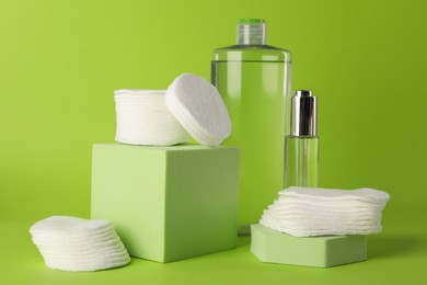 Photo of Clean cotton pads and cosmetic products on green background