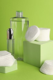 Photo of Clean cotton pads and cosmetic products on green background