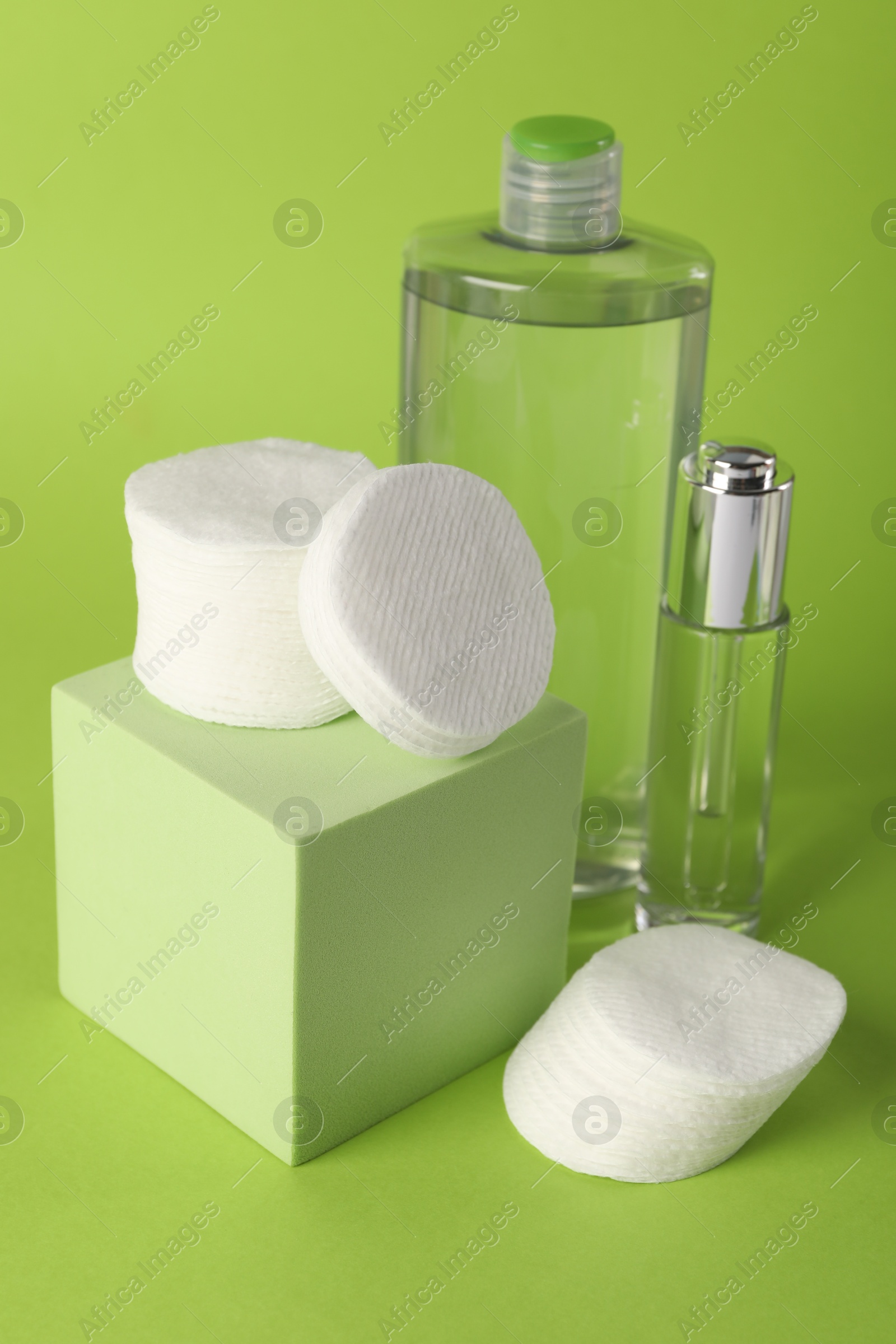 Photo of Clean cotton pads and cosmetic products on green background