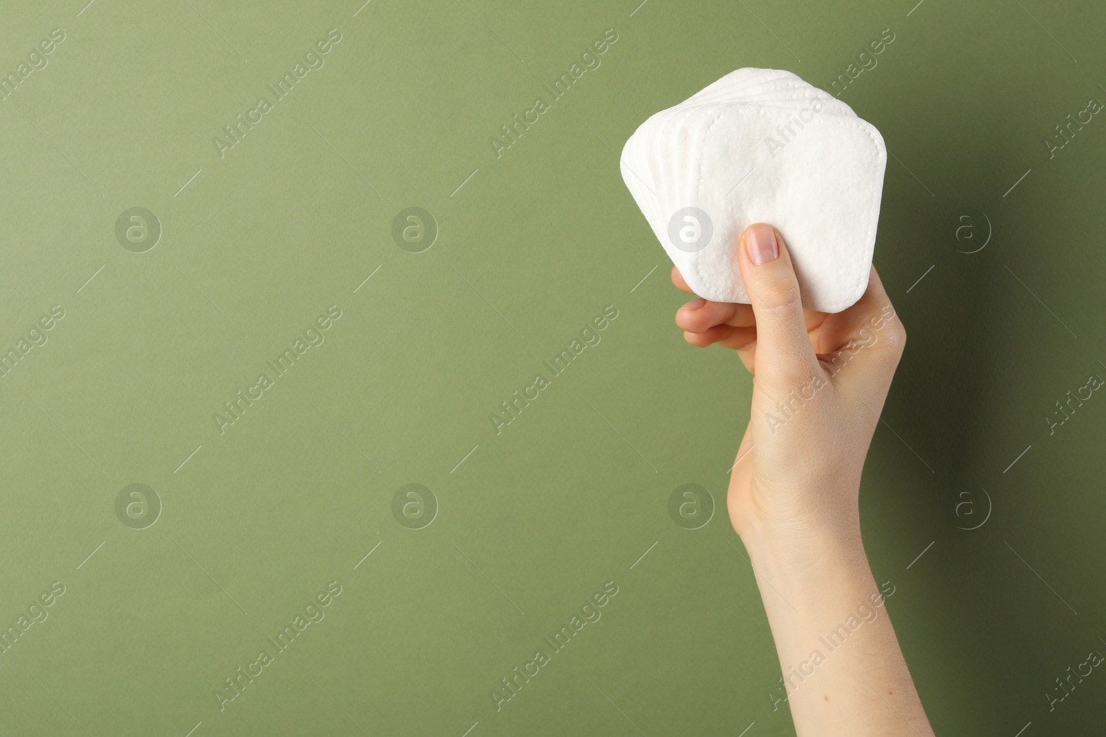 Photo of Woman with clean cotton pads on olive background, closeup. Space for text