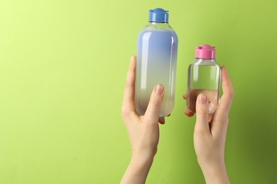 Photo of Woman with bottles of cosmetic products on green background, closeup