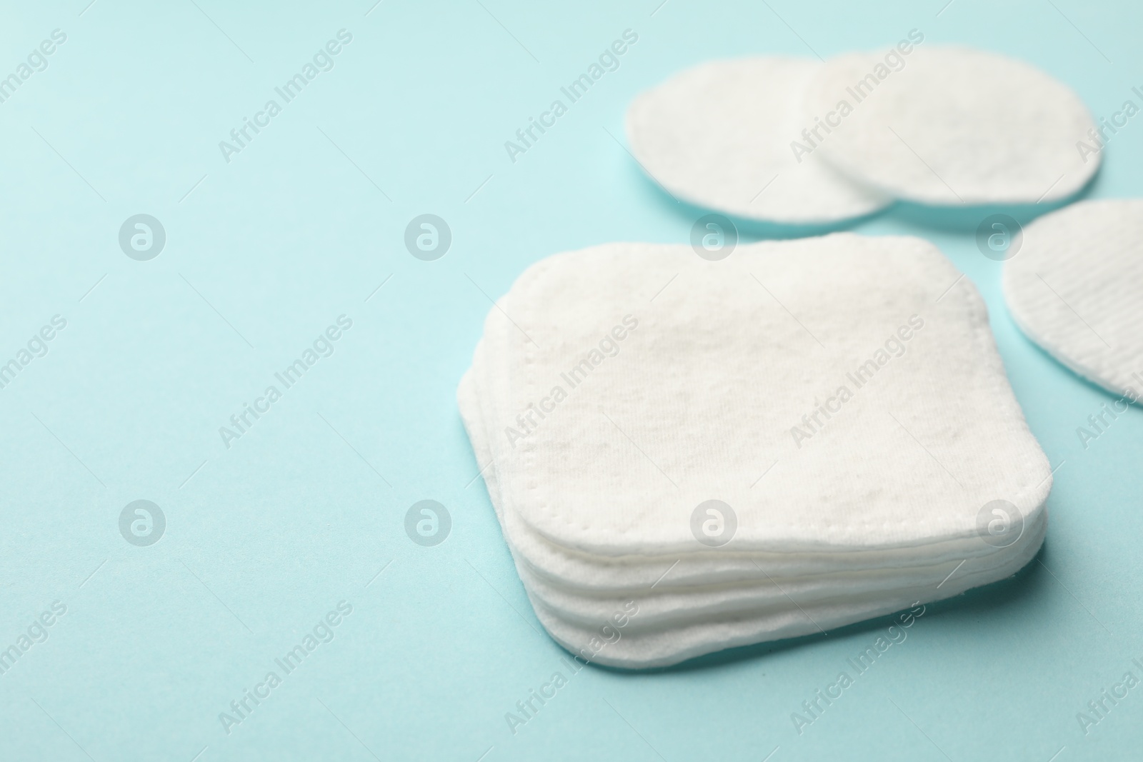 Photo of Clean cotton pads on light blue background, closeup. Space for text