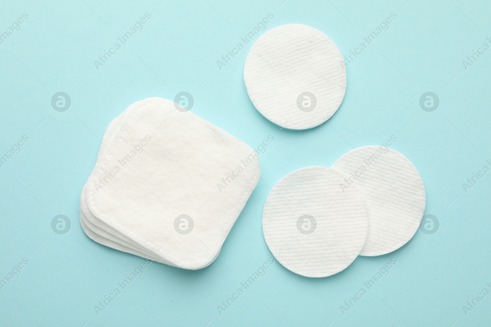 Photo of Clean cotton pads on light blue background, flat lay