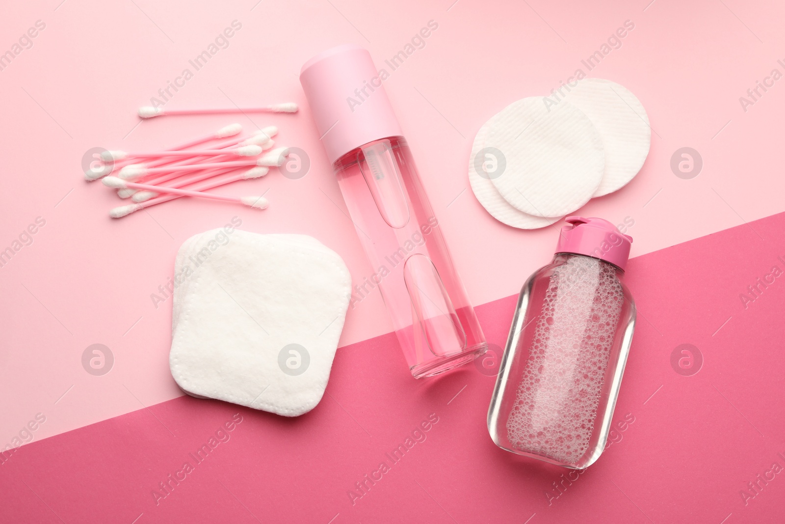 Photo of Cotton pads, swabs and cosmetic products on pink background, flat lay