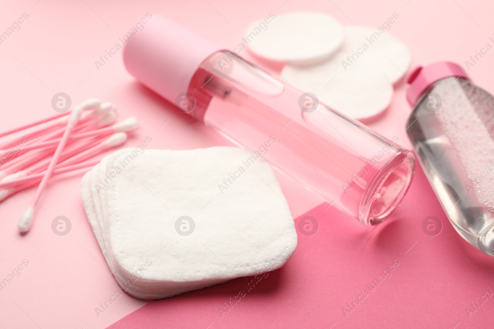 Photo of Cotton pads, swabs and cosmetic products on pink background, closeup