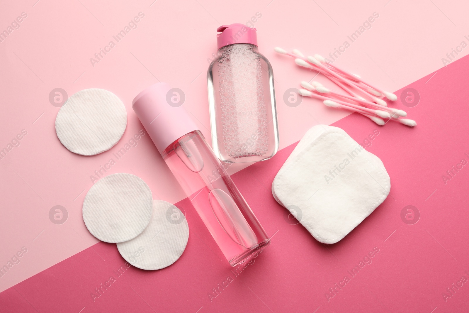 Photo of Cotton pads, swabs and cosmetic products on pink background, flat lay