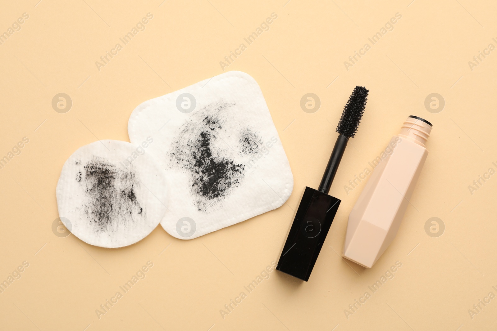 Photo of Dirty cotton pads and mascara on beige background, flat lay