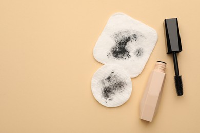 Photo of Dirty cotton pads and mascara on beige background, flat lay. Space for text