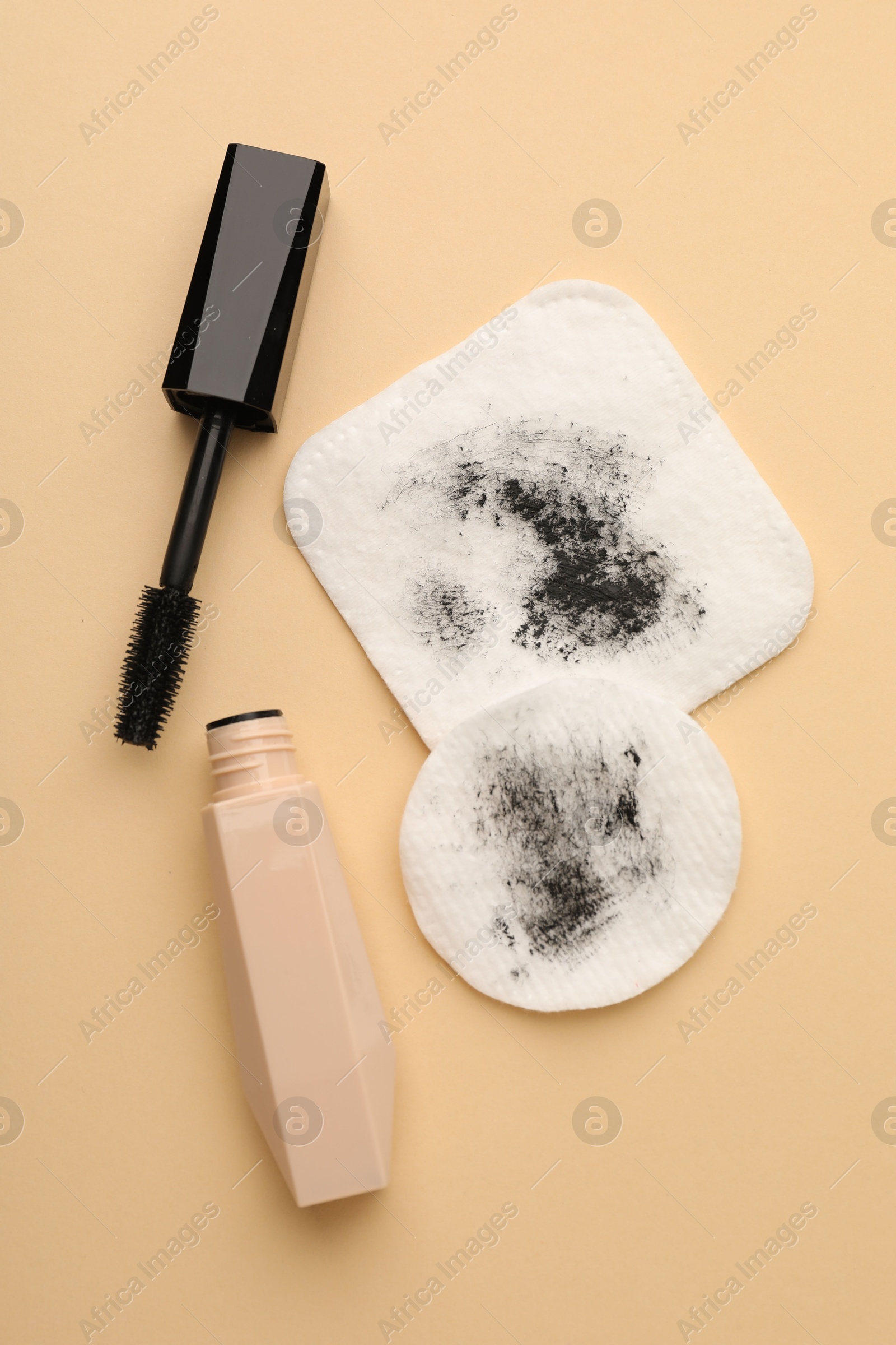 Photo of Dirty cotton pads and mascara on beige background, flat lay