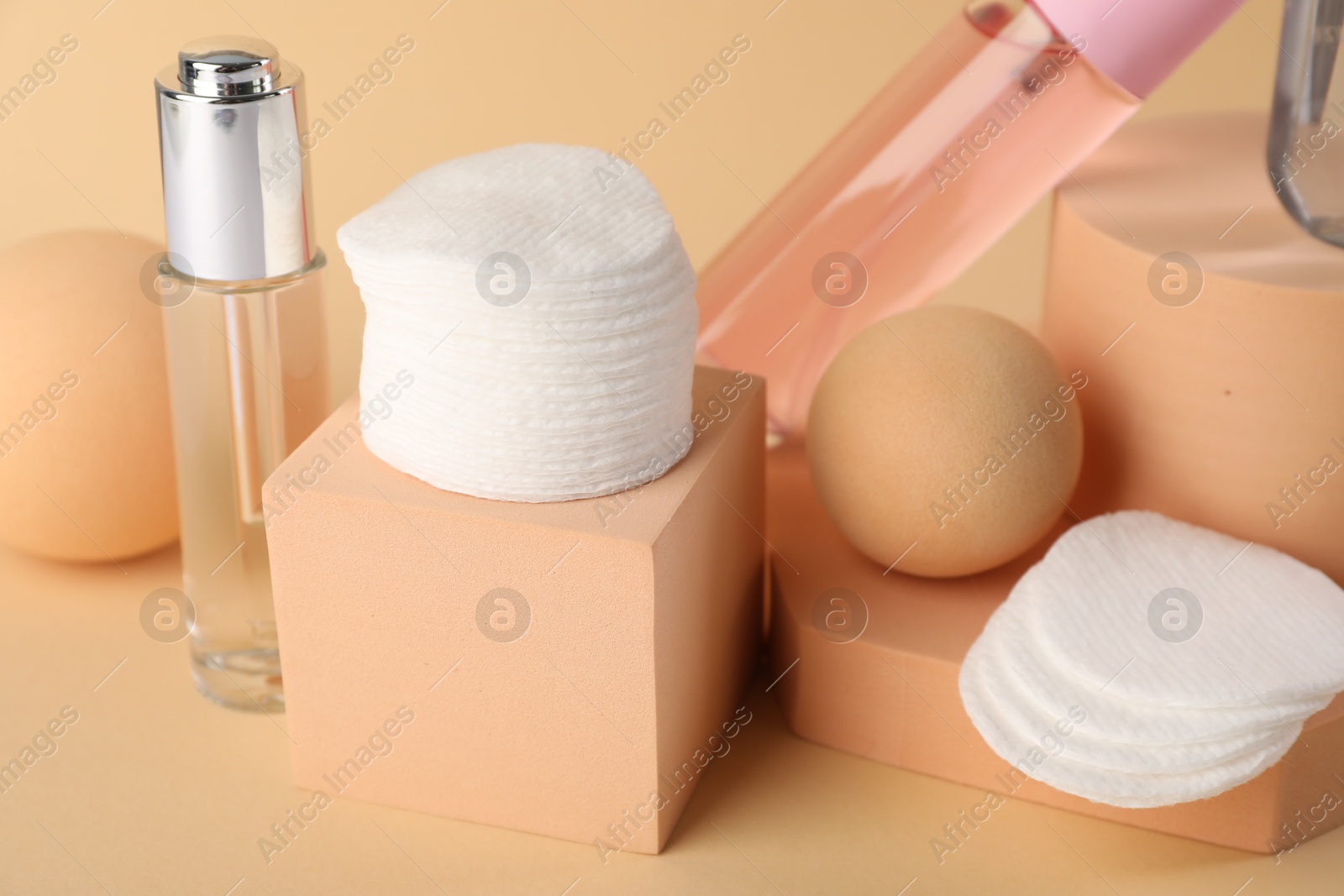 Photo of Clean cotton pads and cosmetic products on beige background, closeup