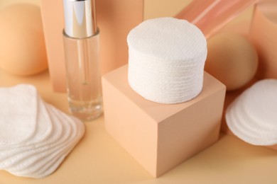 Photo of Clean cotton pads and cosmetic products on beige background, closeup