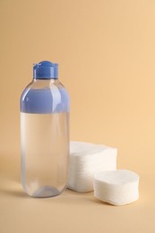 Photo of Clean cotton pads and micellar water on beige background