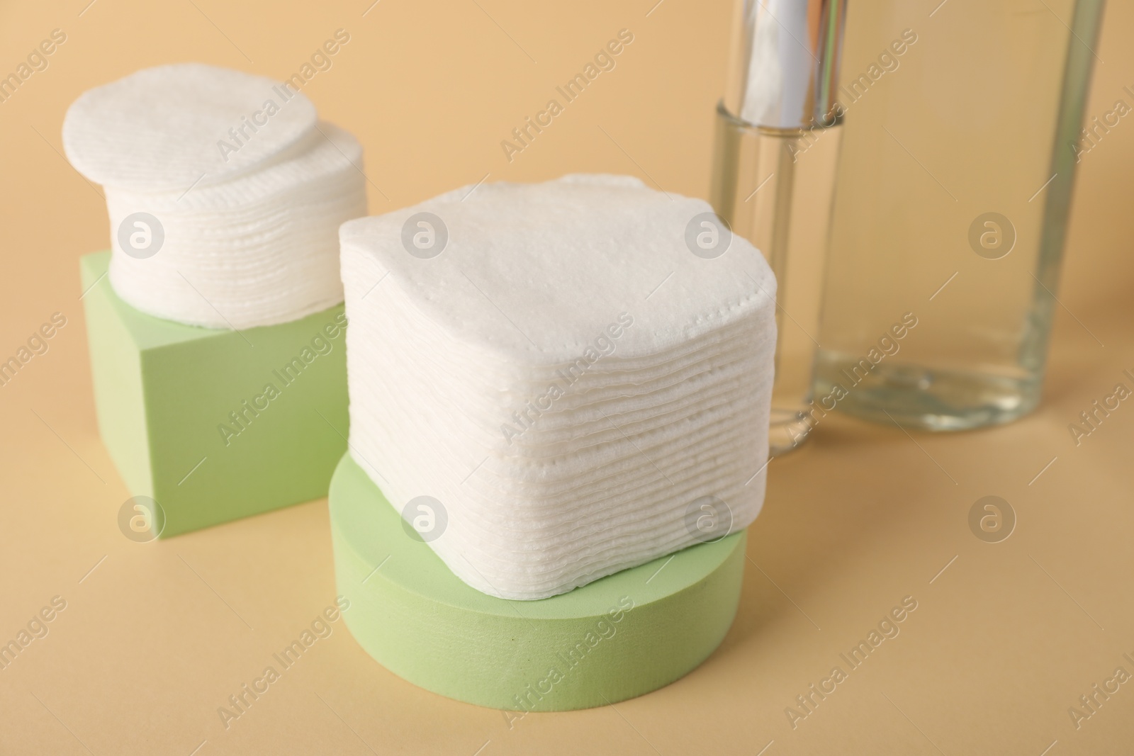 Photo of Clean cotton pads and cosmetic products on beige background, closeup