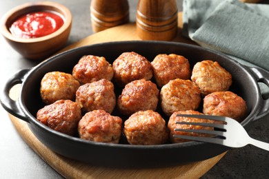 Photo of Tasty meatballs in baking dish served on grey table, closeup