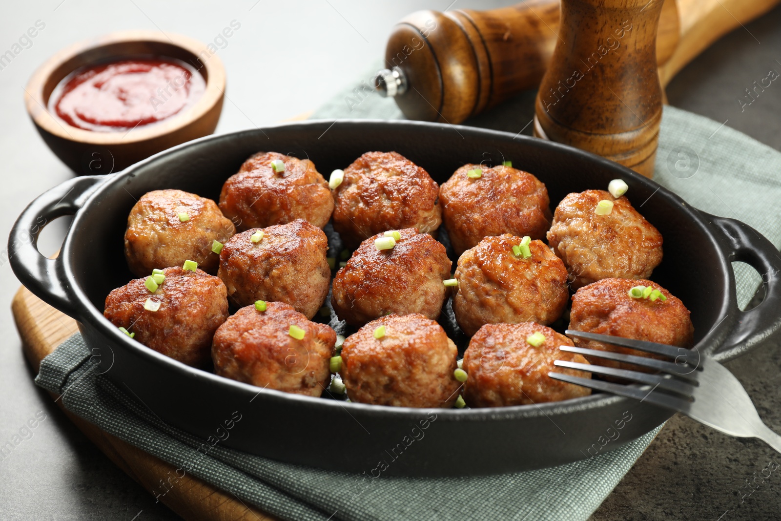 Photo of Tasty meatballs in baking dish served on grey table, closeup