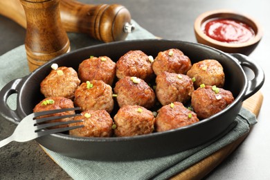 Photo of Tasty meatballs in baking dish served on grey table, closeup