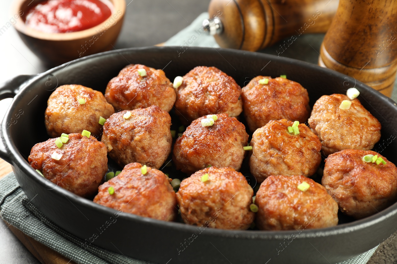 Photo of Tasty meatballs in baking dish on grey table, closeup