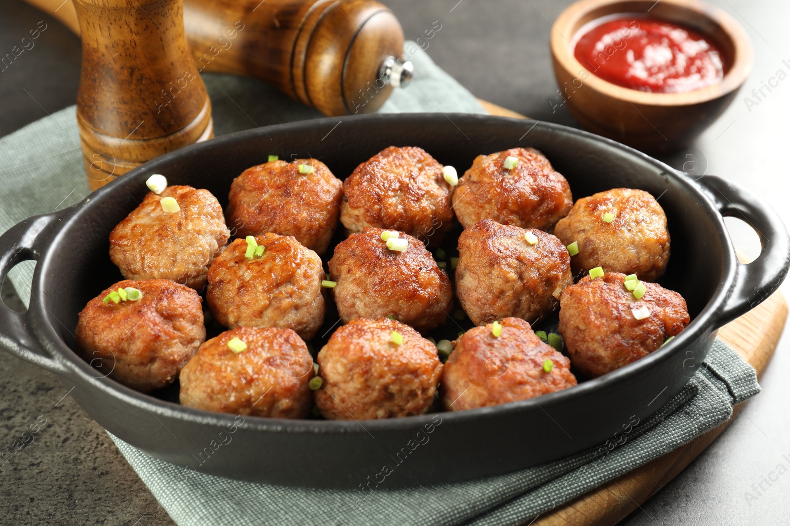 Photo of Tasty meatballs in baking dish served on grey table