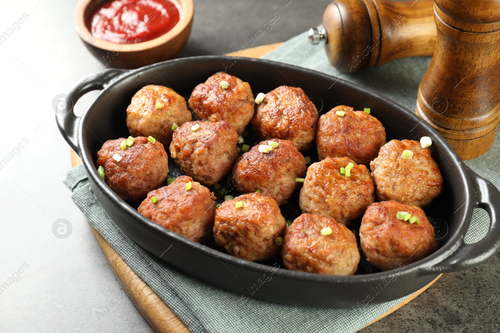 Photo of Tasty meatballs in baking dish served on grey table