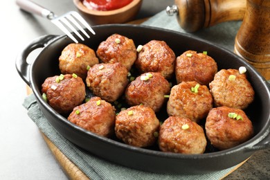 Photo of Tasty meatballs in baking dish served on grey table, closeup