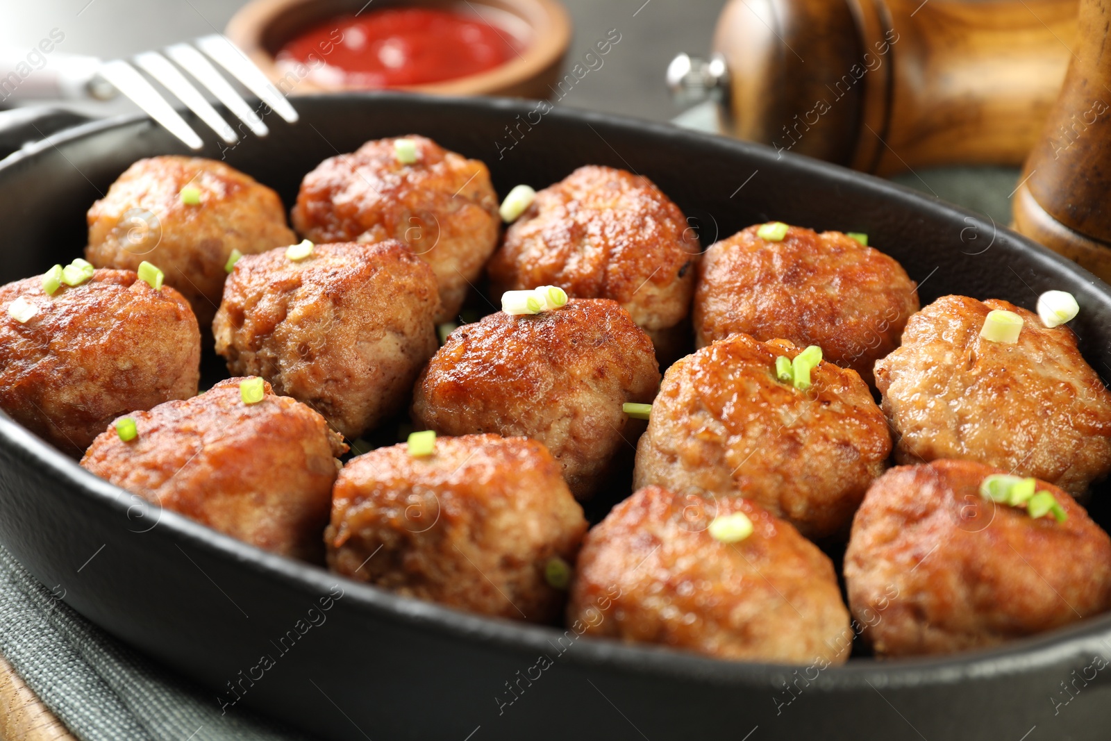 Photo of Tasty meatballs in baking dish on grey table, closeup