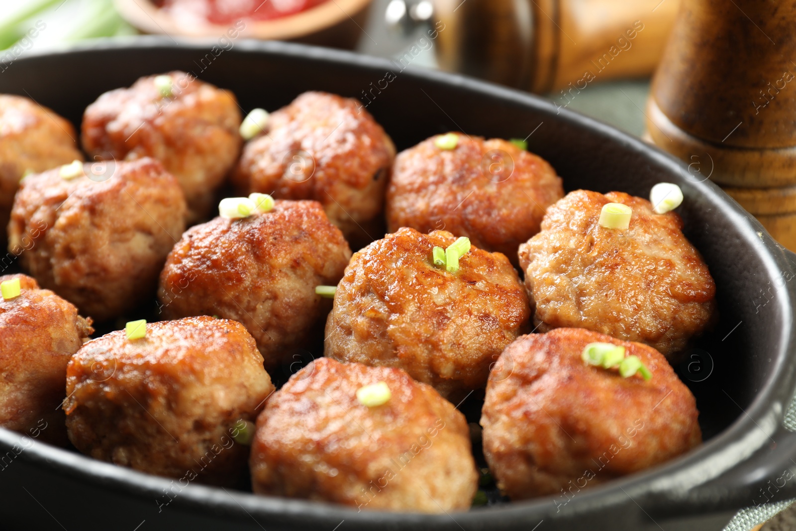 Photo of Tasty meatballs with green onion in baking dish on table, closeup