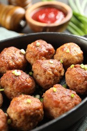 Photo of Tasty meatballs with green onion in baking dish on table, closeup