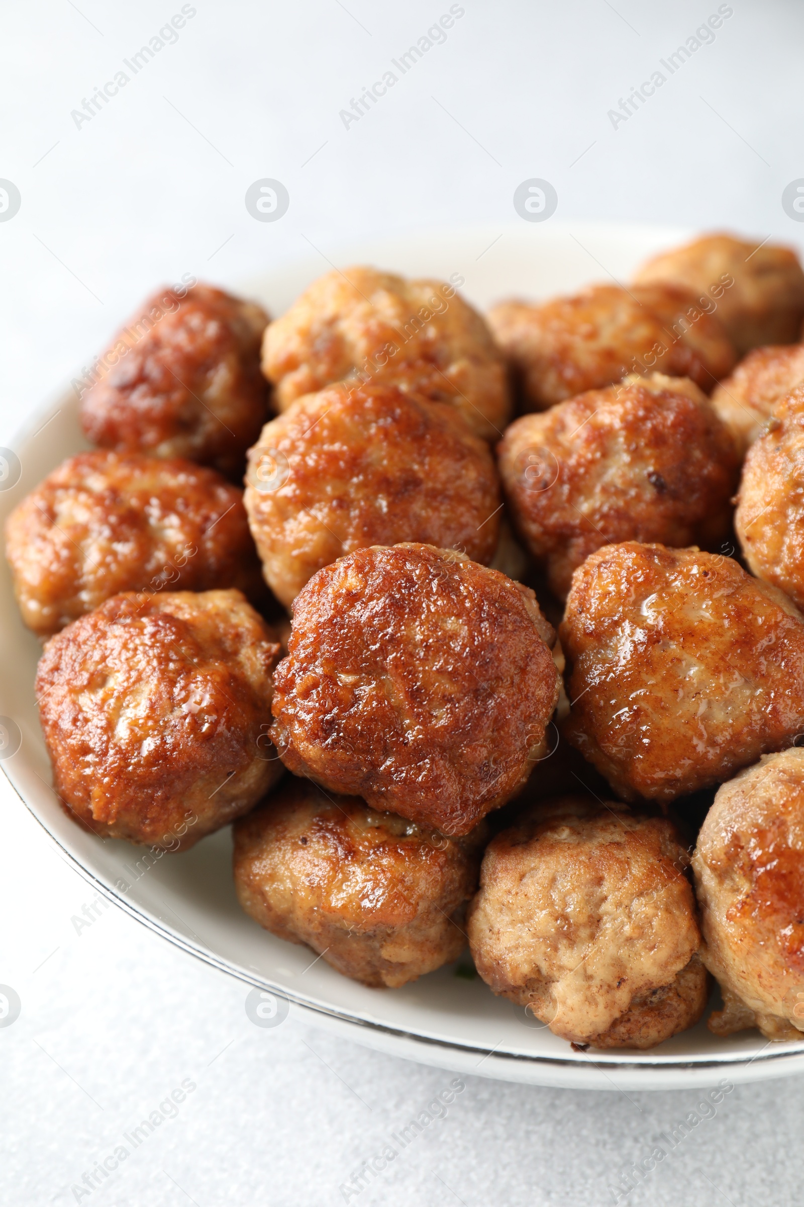 Photo of Tasty cooked meatballs in bowl on white table, closeup