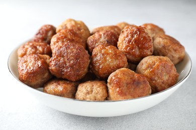 Photo of Tasty cooked meatballs in bowl on white table, closeup