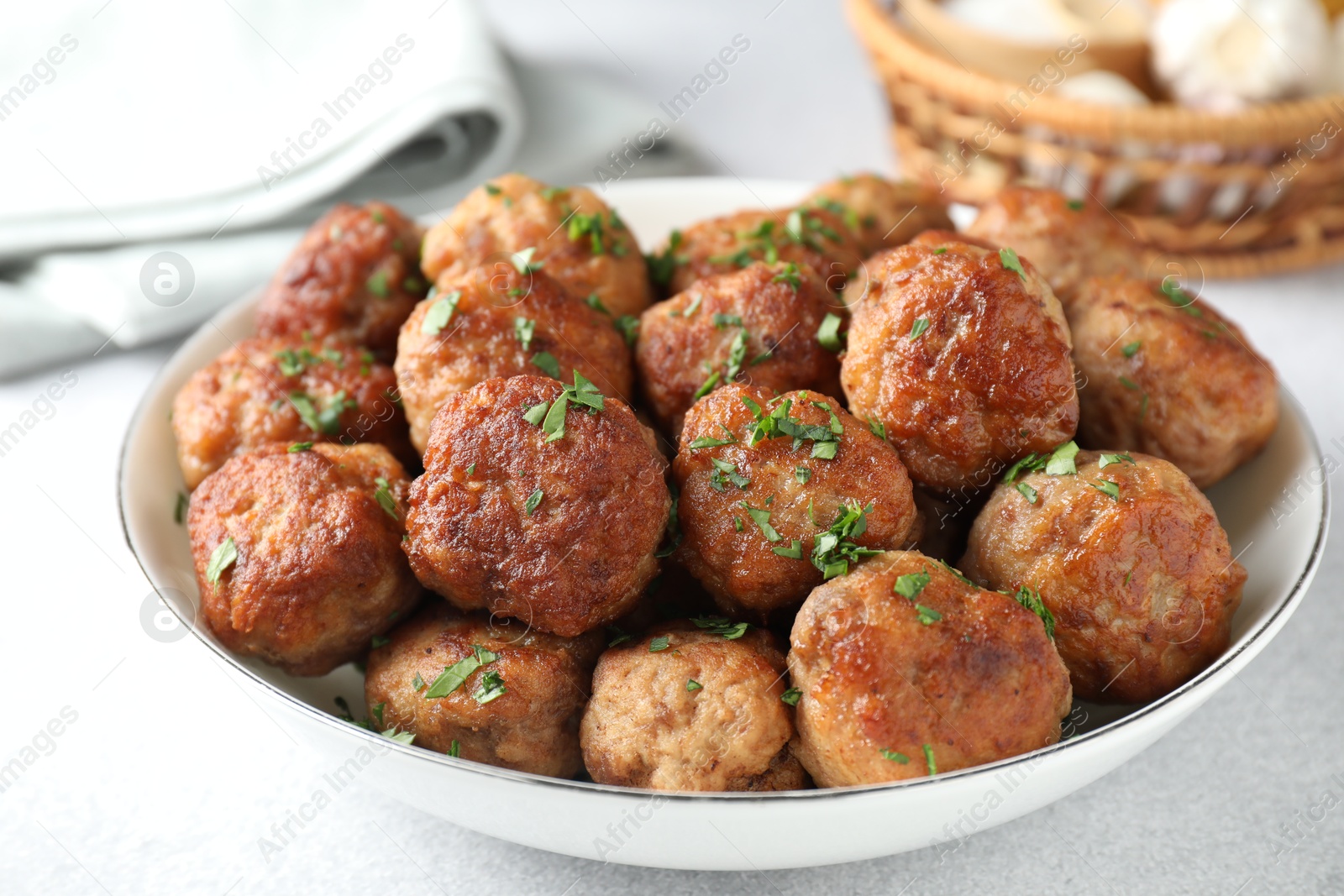 Photo of Tasty cooked meatballs with green onion in bowl on white table, closeup