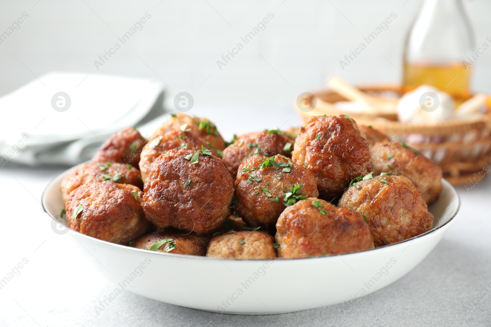 Photo of Tasty cooked meatballs with green onion in bowl on white table, closeup