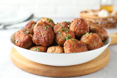 Photo of Tasty cooked meatballs with green onion in bowl on white table, closeup