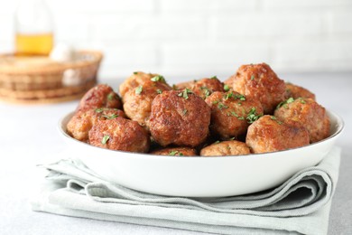 Photo of Tasty cooked meatballs with green onion in bowl on white table, closeup