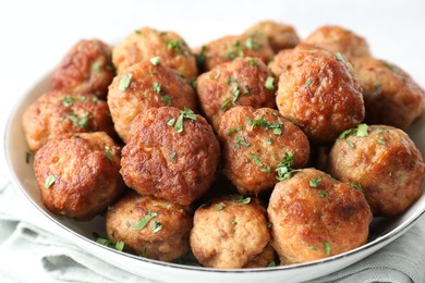 Photo of Tasty cooked meatballs with green onion in bowl on white table, closeup