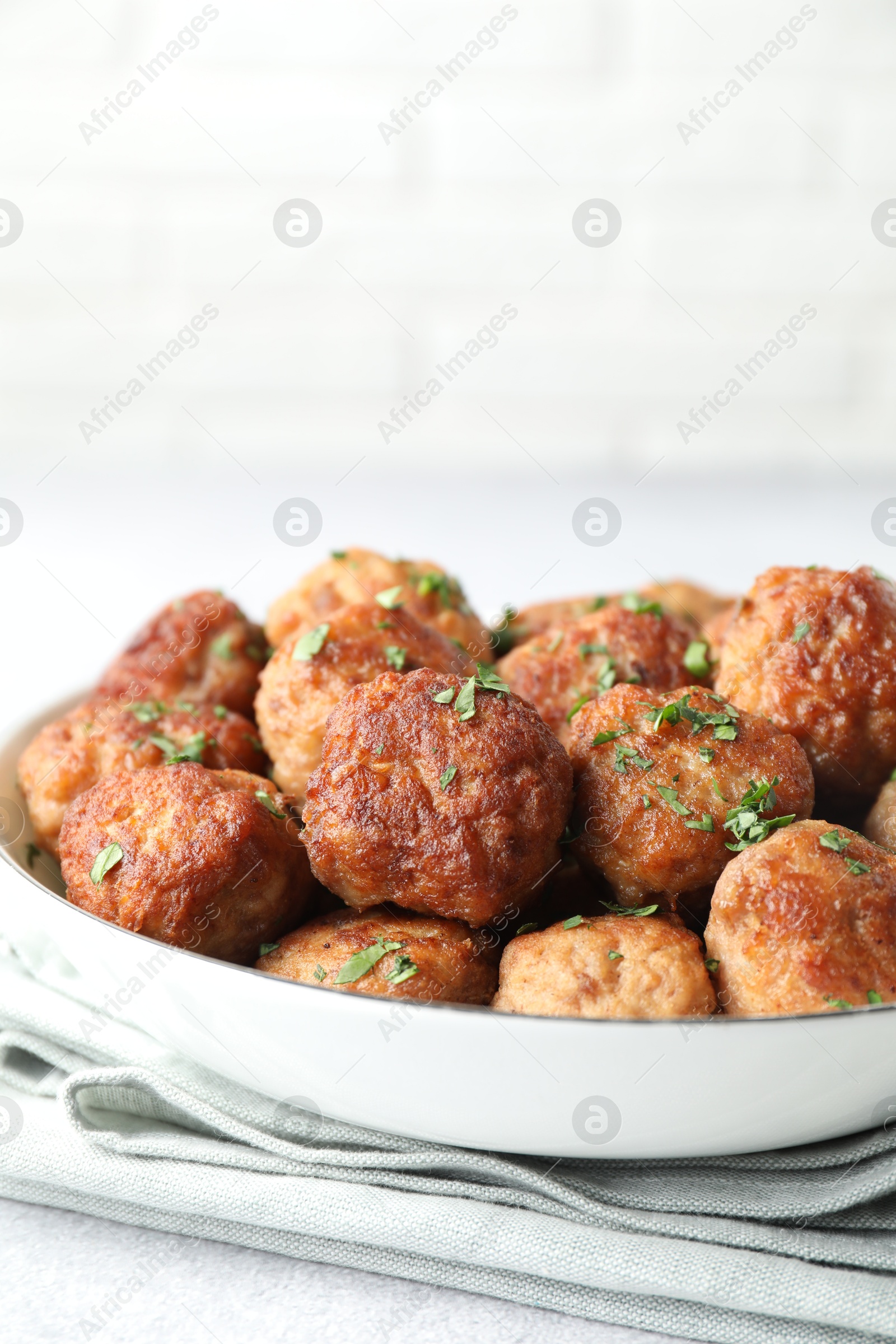 Photo of Tasty cooked meatballs with green onion in bowl on white table, closeup