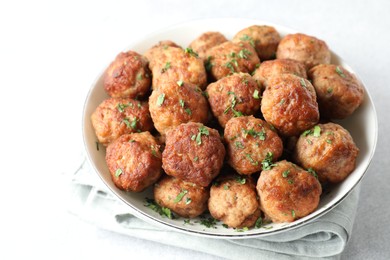 Photo of Tasty cooked meatballs with green onion in bowl on white table, closeup