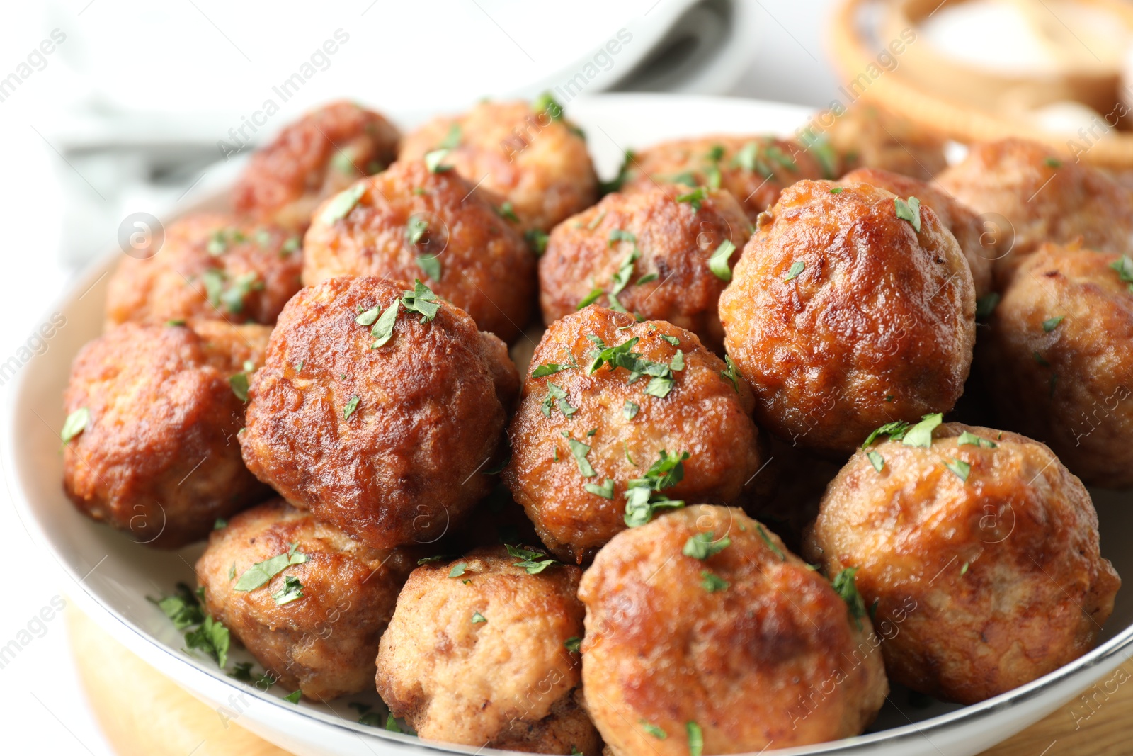 Photo of Tasty cooked meatballs with green onion in bowl on white table, closeup