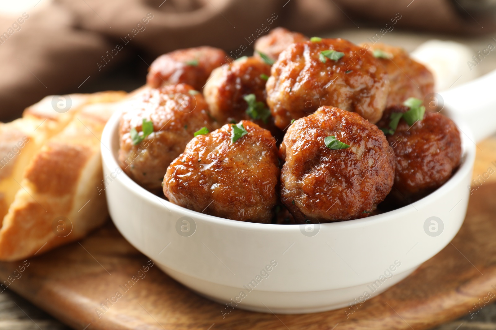 Photo of Tasty meatballs with green onion in baking dish on wooden table, closeup