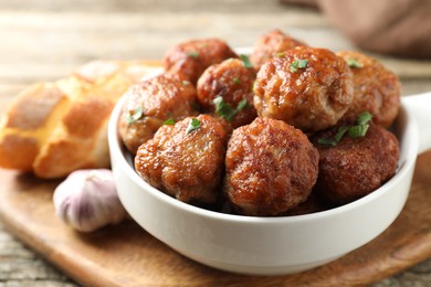 Photo of Tasty meatballs with green onion in baking dish on wooden table, closeup