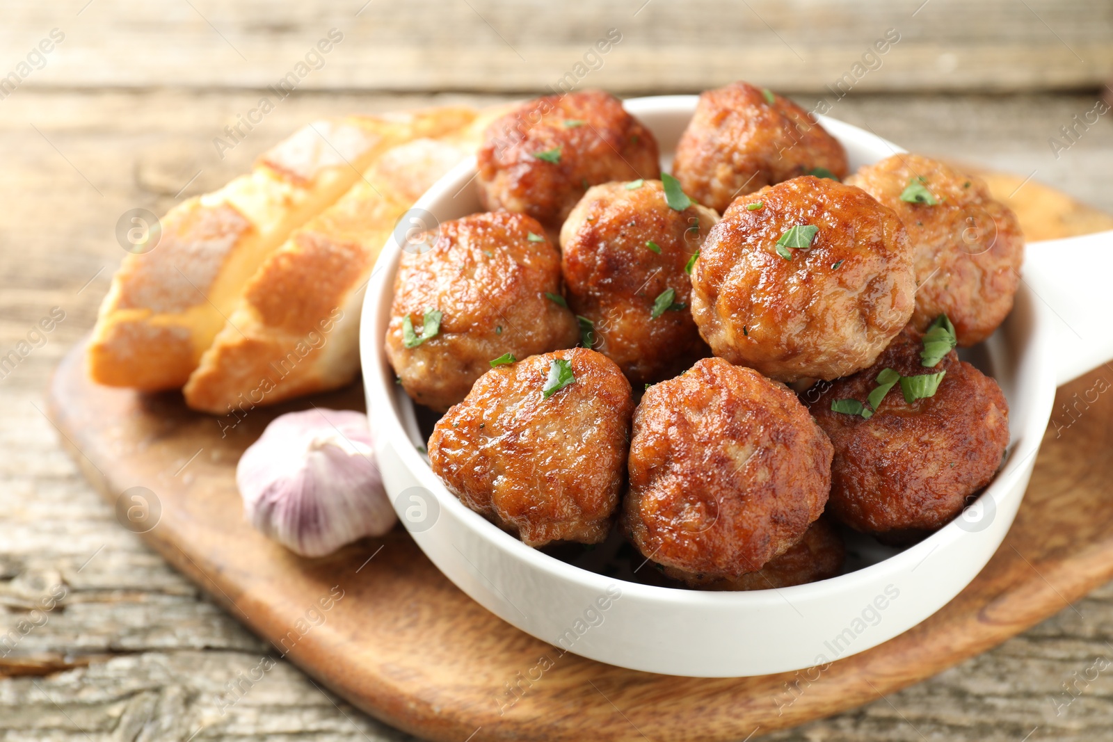 Photo of Tasty meatballs with green onion in baking dish on wooden table, closeup