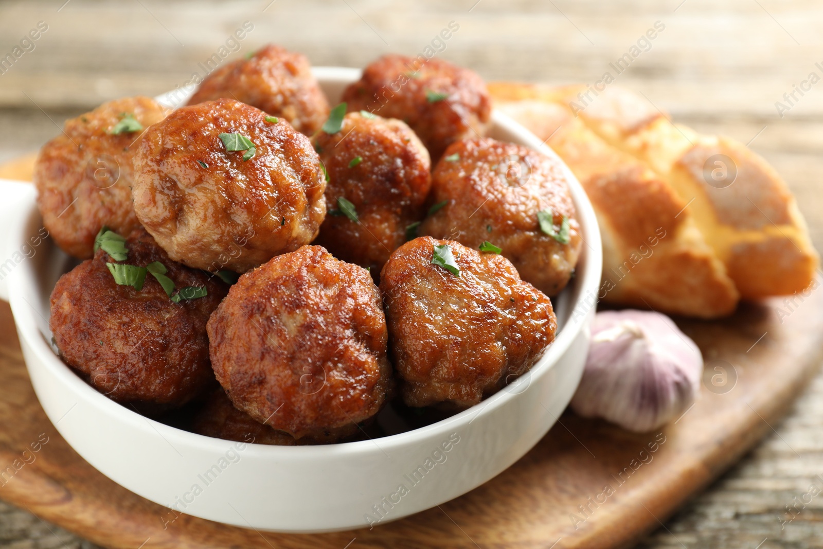 Photo of Tasty meatballs with green onion in baking dish on wooden table, closeup