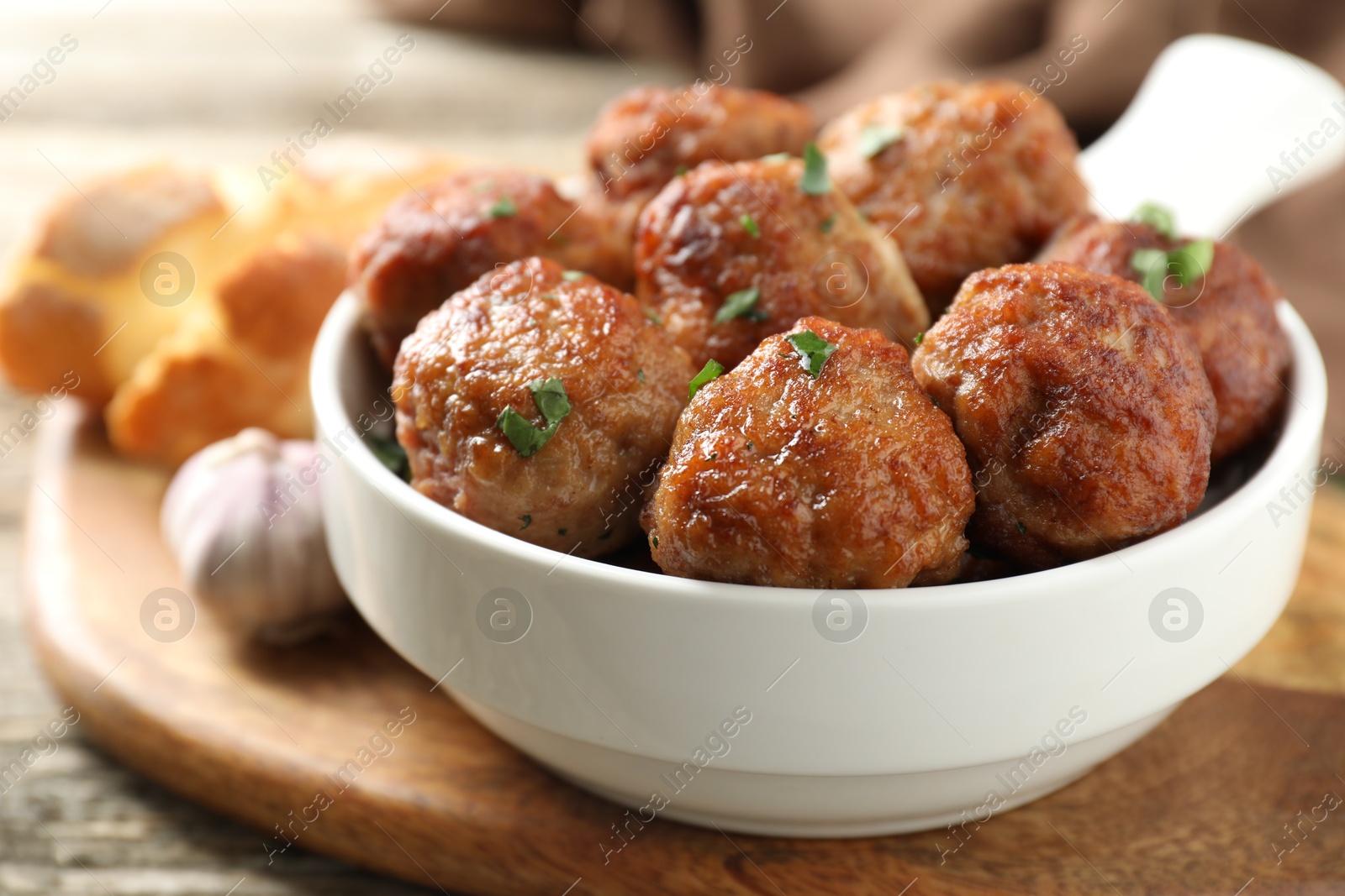 Photo of Tasty meatballs with green onion in baking dish on wooden table, closeup