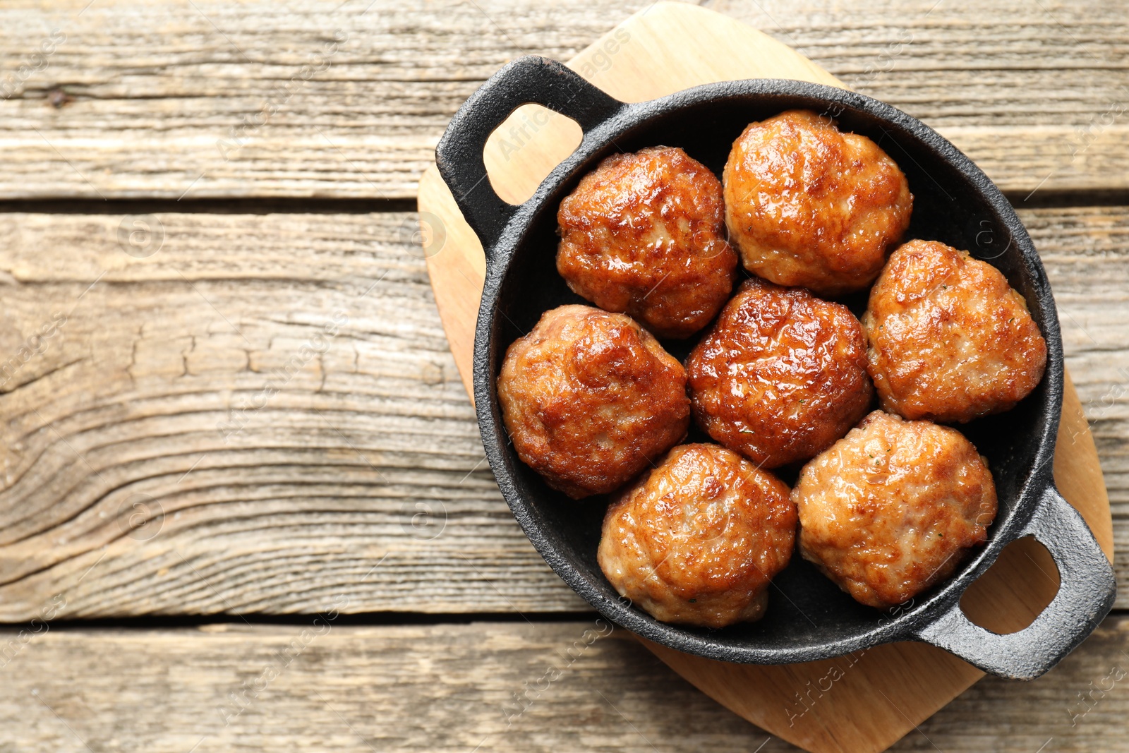 Photo of Tasty meatballs in baking dish on wooden table, top view. Space for text