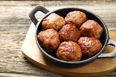 Photo of Tasty meatballs in baking dish on wooden table, closeup