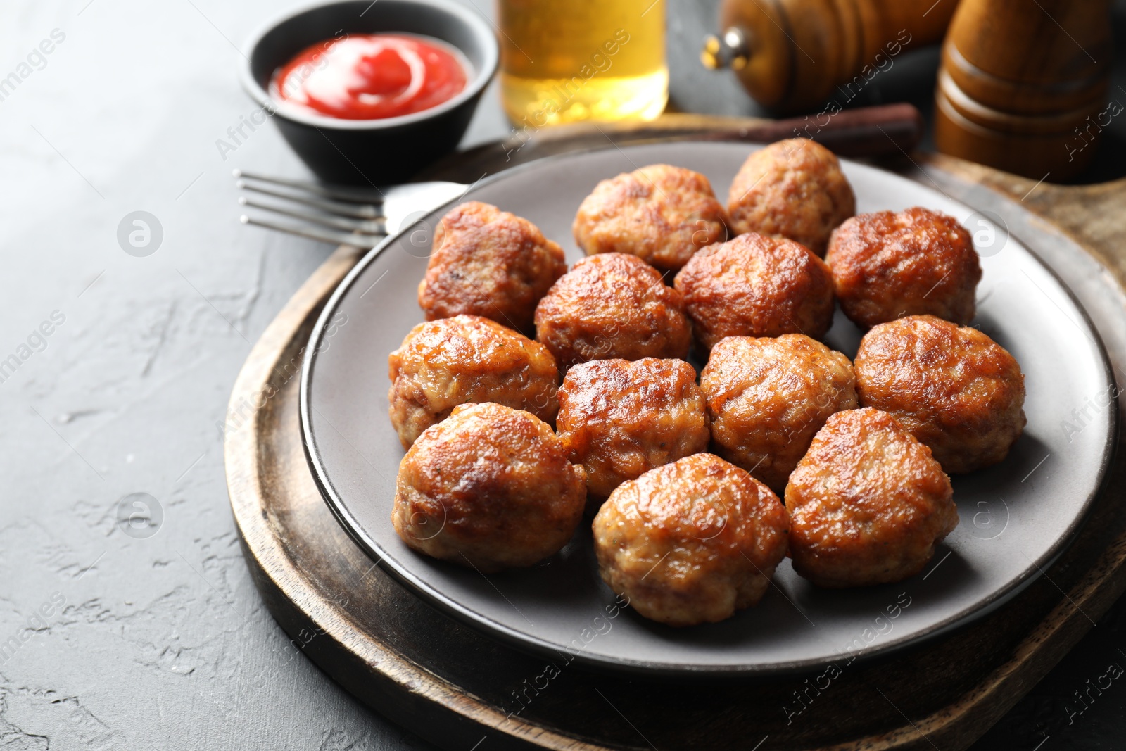 Photo of Tasty cooked meatballs served on grey table