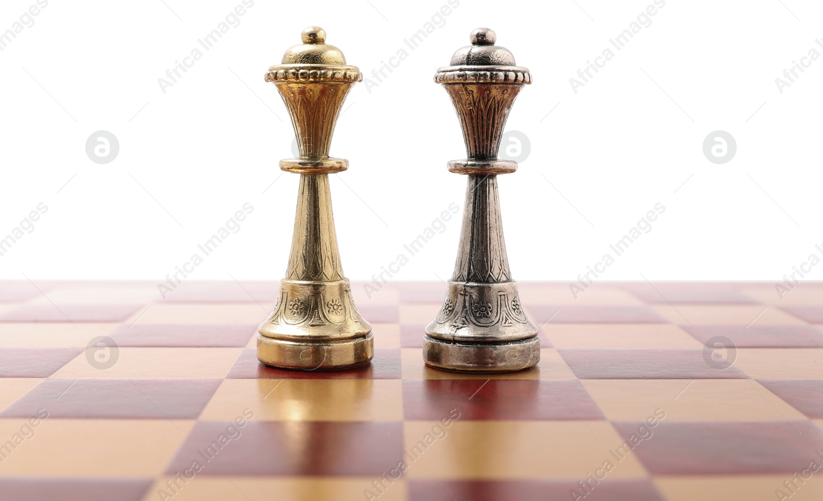 Photo of Golden and silver chess queens on wooden checkerboard against white background. Competition concept