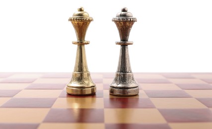 Photo of Golden and silver chess queens on wooden checkerboard against white background. Competition concept