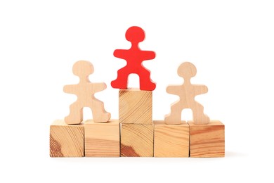 Photo of Human figures on wooden blocks, red one on top against white background. Competition concept