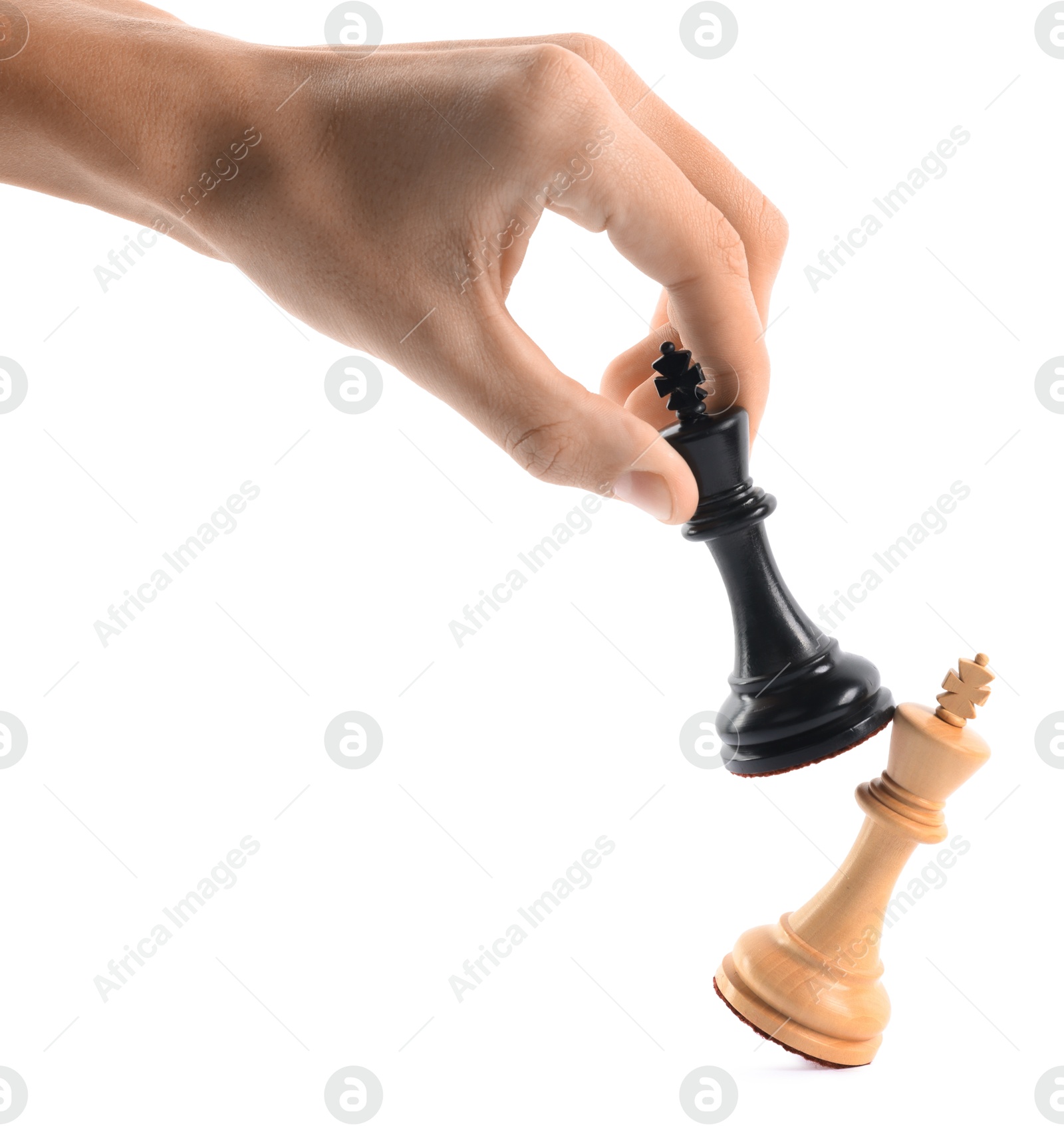 Photo of Man with black chess king knocking over white one on white background, closeup. Competition concept