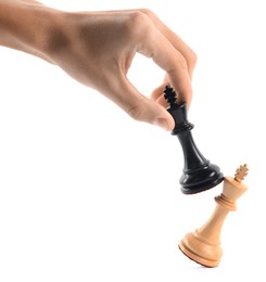 Photo of Man with black chess king knocking over white one on white background, closeup. Competition concept